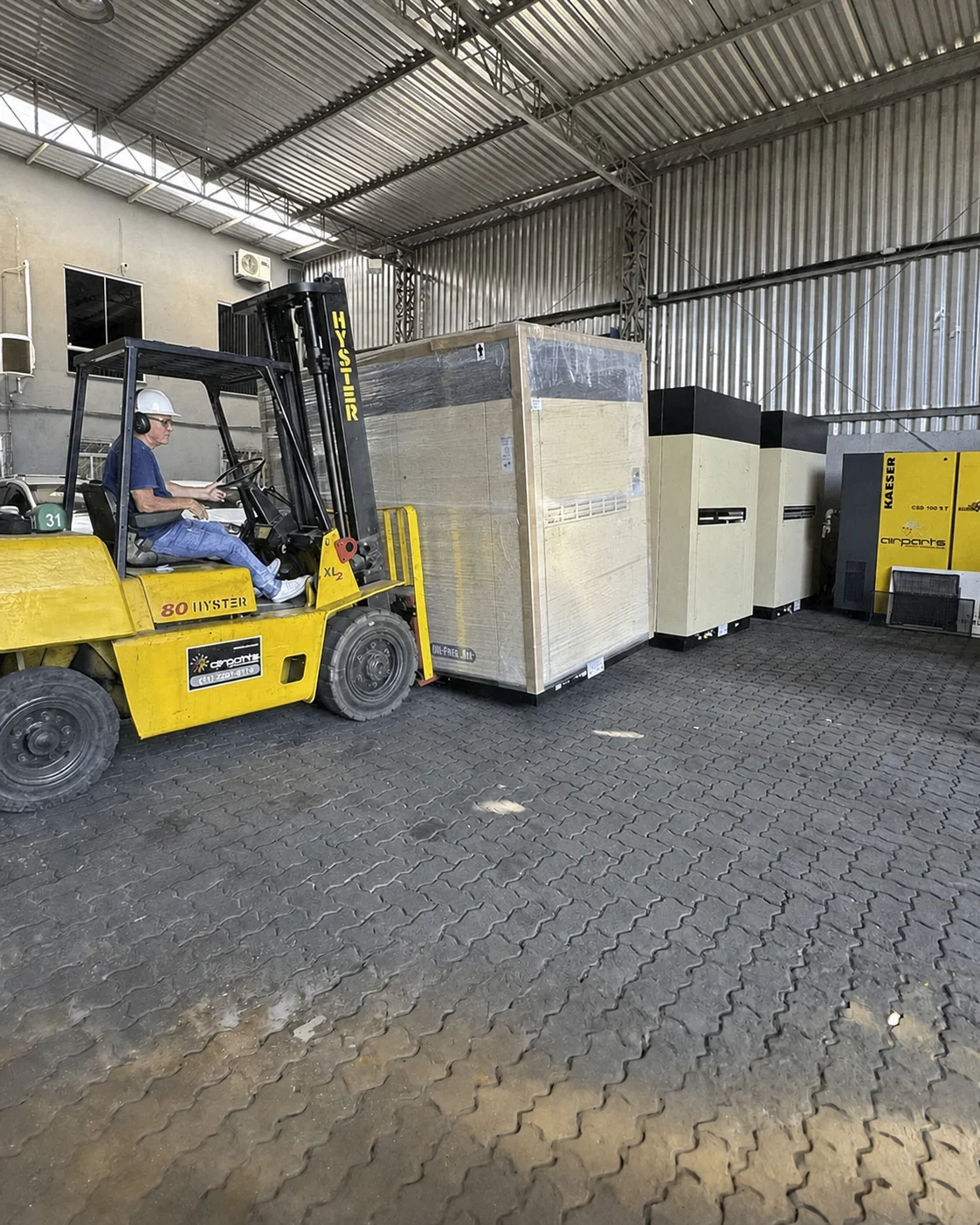 Compressor isento de óleo Rental Parts transportado em empilhadeira com operador utilizando EPI completo